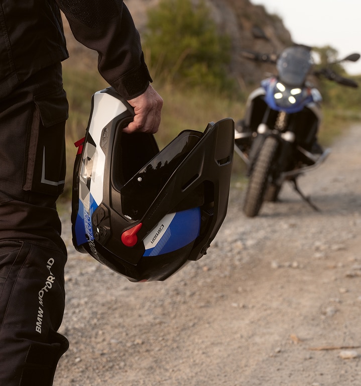 Osoba trzyma w ręku kask motocyklowy. 