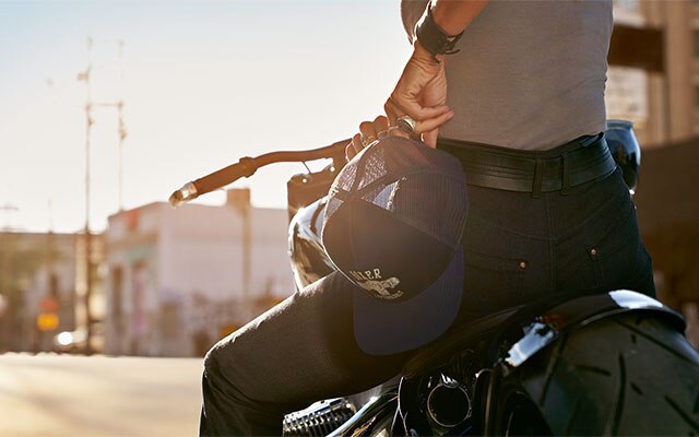 Motocyklistka ubrana w damskie jeansy RoadCrafted trzyma w dłoni czapkę Boxer.